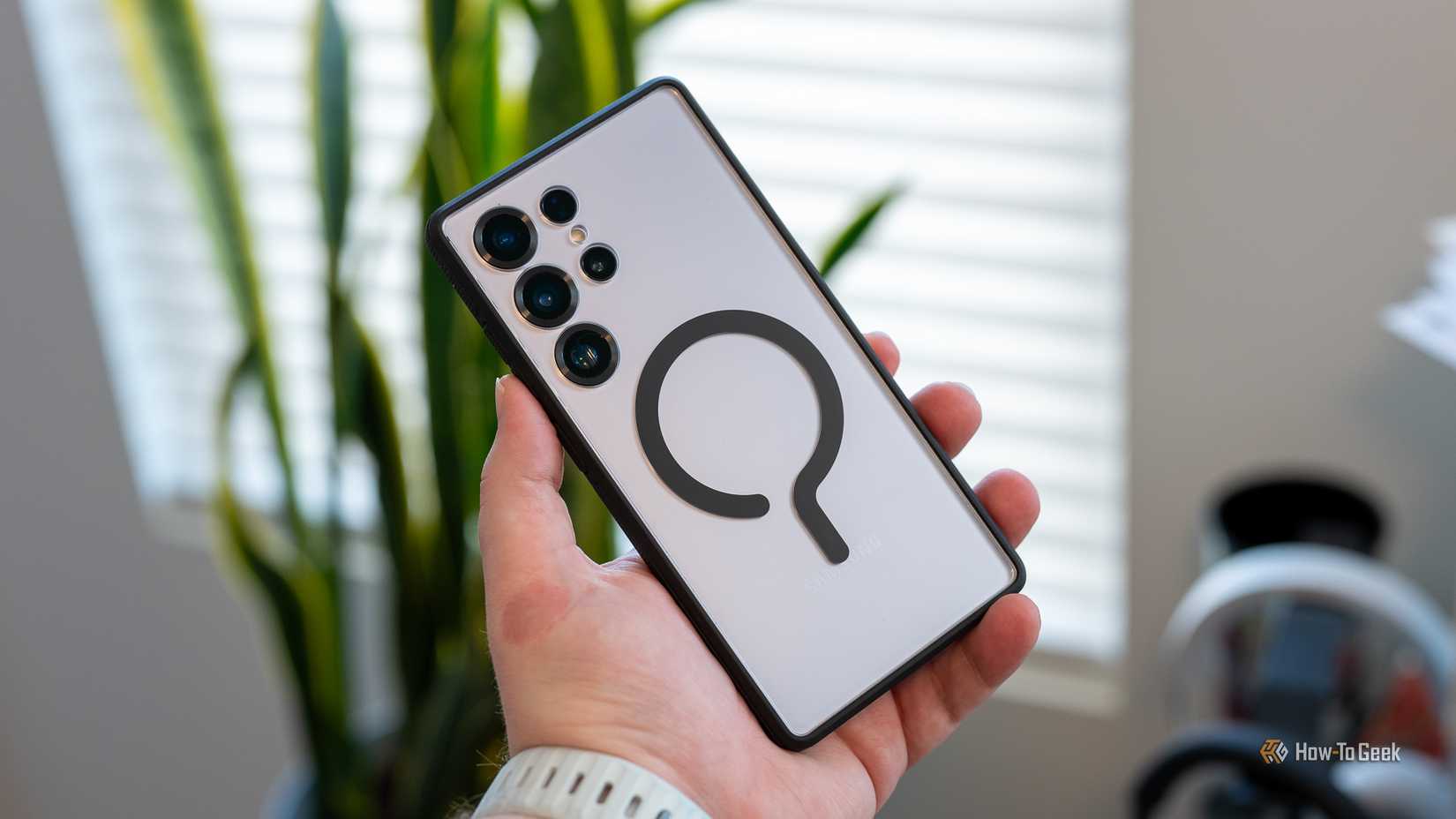 Person holding the Samsung Galaxy S25 Ultra protected by the dbrand Ghost 2.0 clear case.