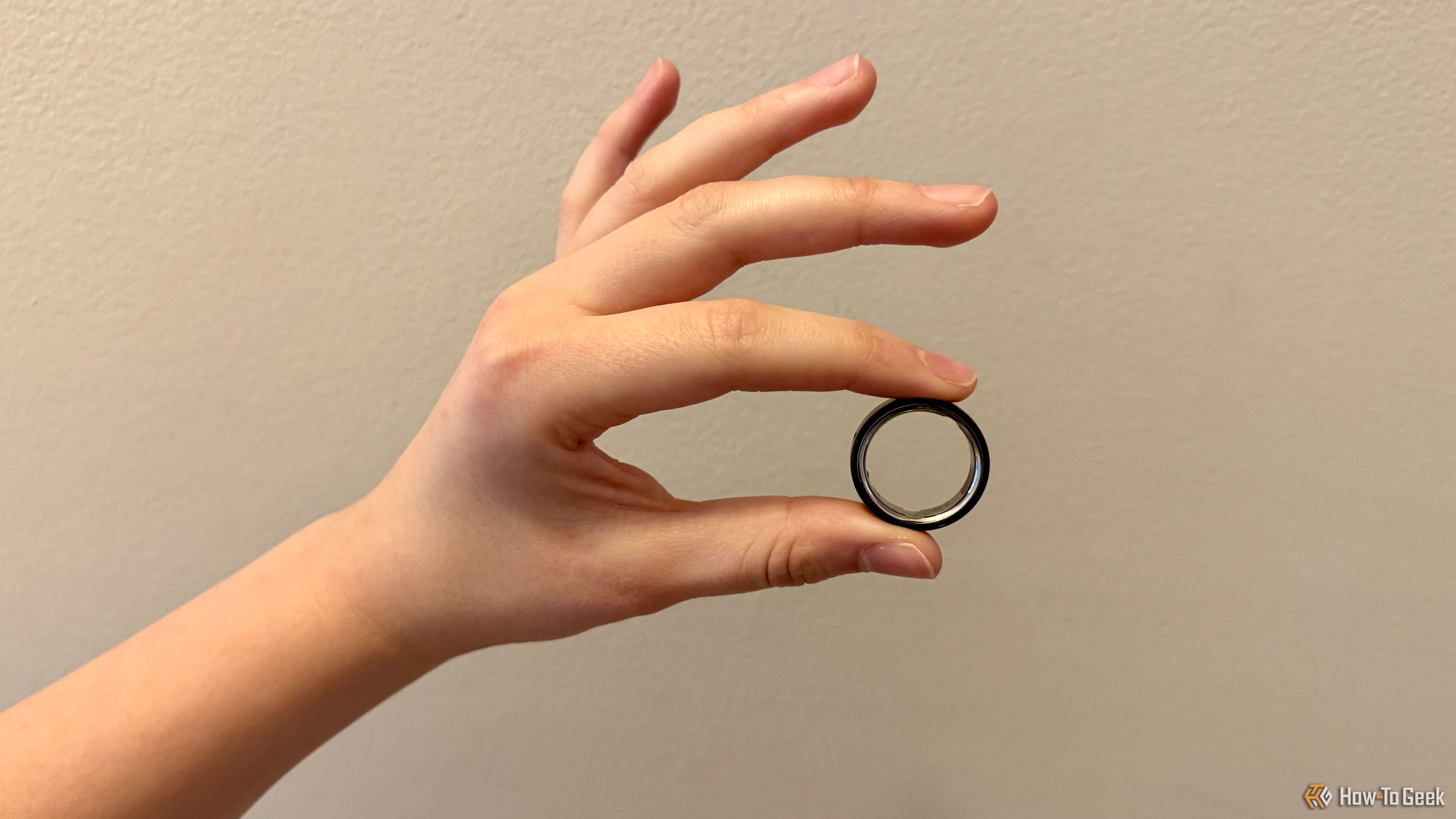 Oura Ring 4 sendo segurado entre o dedo indicador e o polegar.