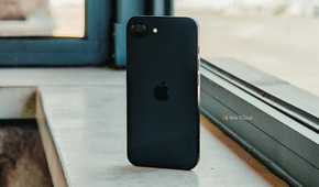 iPhone 16e back (angled) in front of window.