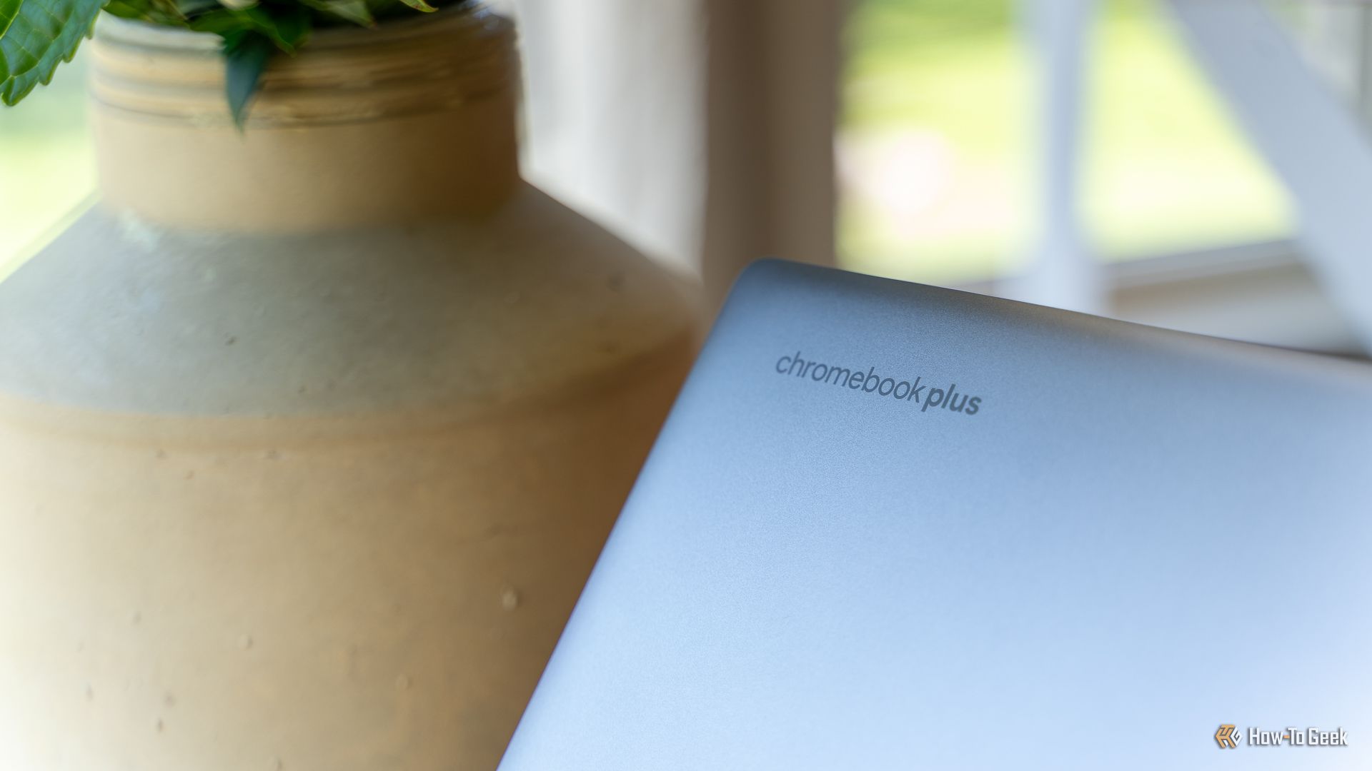 A tampa do HP Chromebook Plus x360 14b mostrando o logotipo do Chromebook Plus com uma planta ao fundo.