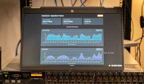 A laptop showing the Speedtest-Tracker Docker container sitting on top of a server.