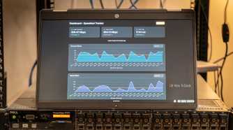 A laptop showing the Speedtest-Tracker Docker container sitting on top of a server.