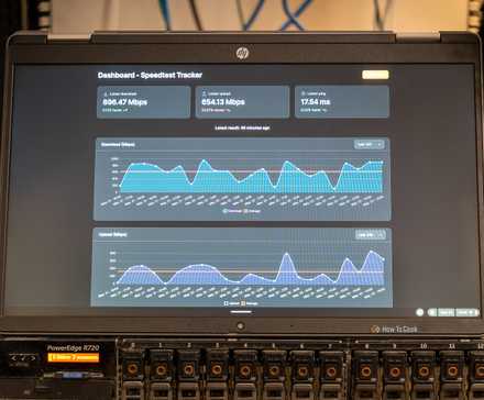 A laptop showing the Speedtest-Tracker Docker container sitting on top of a server.