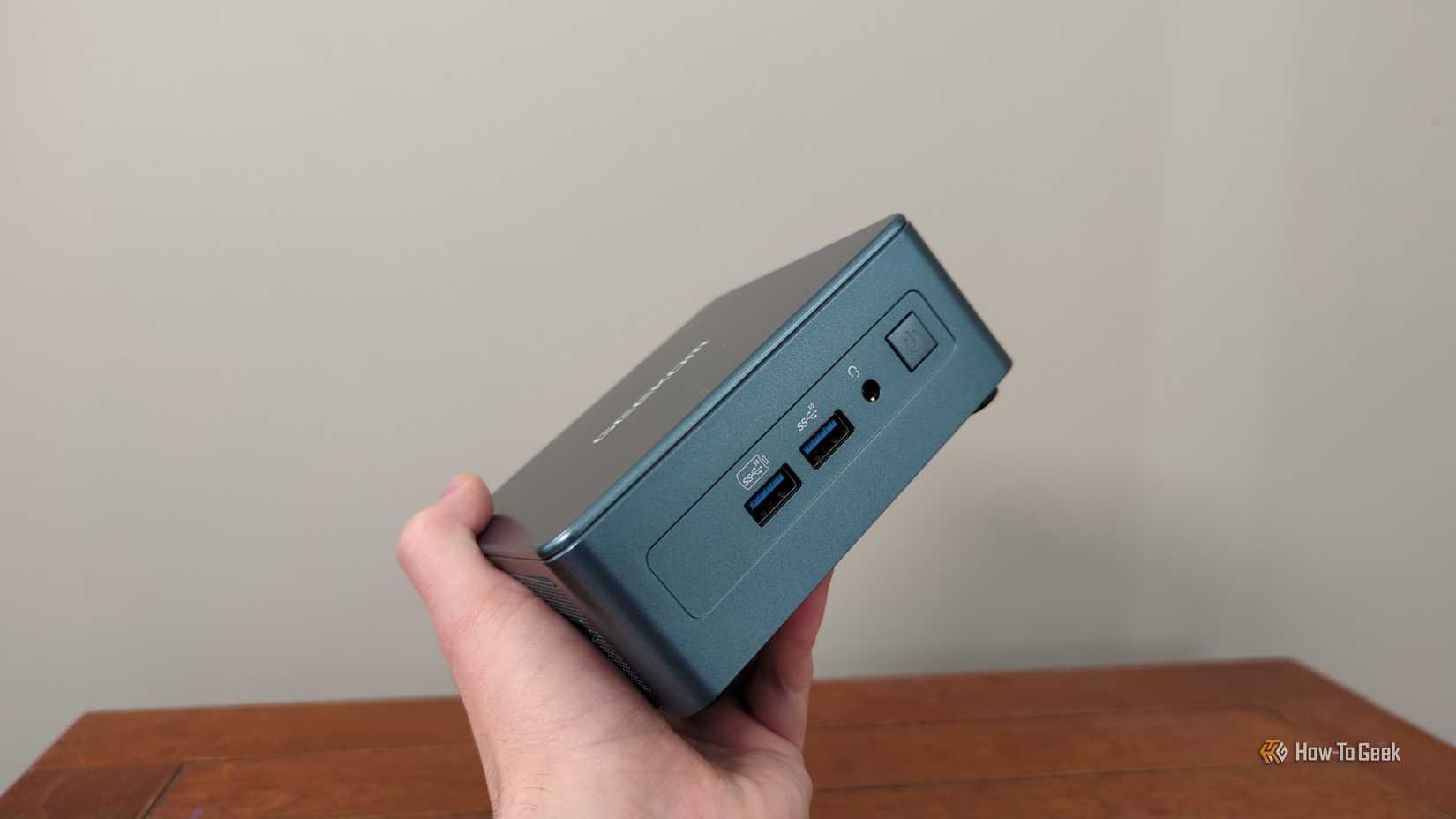 A person's hand holding a Geekom.-1 mini PC