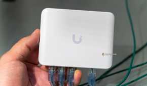 The Unifi Flex Mini 2.5G Ethernet switch with Ethernet cables plugged in being held in a hand.