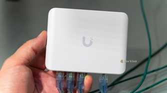 The Unifi Flex Mini 2.5G Ethernet switch with Ethernet cables plugged in being held in a hand.