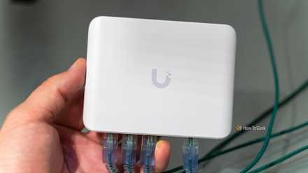 The Unifi Flex Mini 2.5G Ethernet switch with Ethernet cables plugged in being held in a hand.