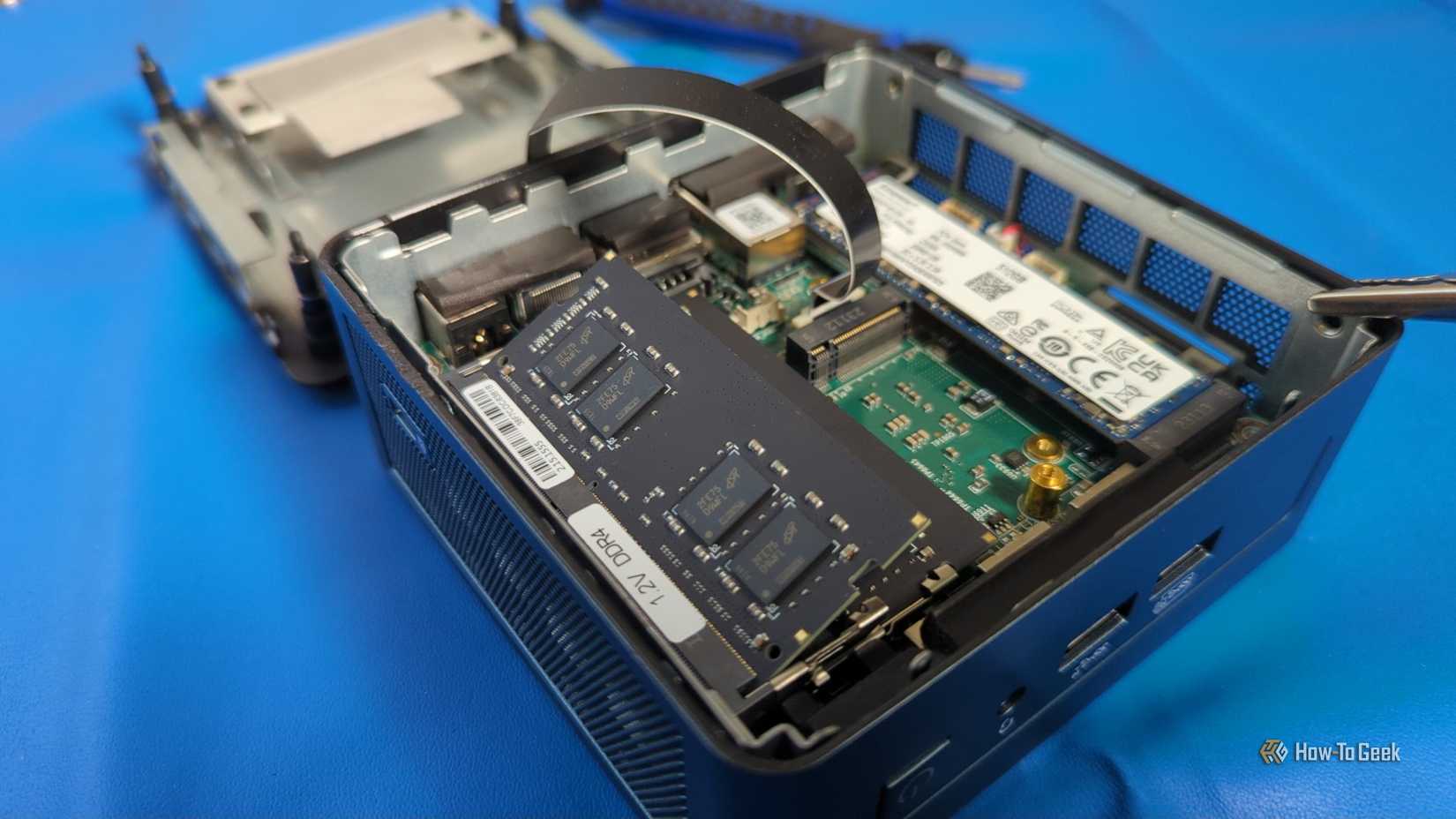 An opened mini PC with parts visible and a RAM stick unseated.-1