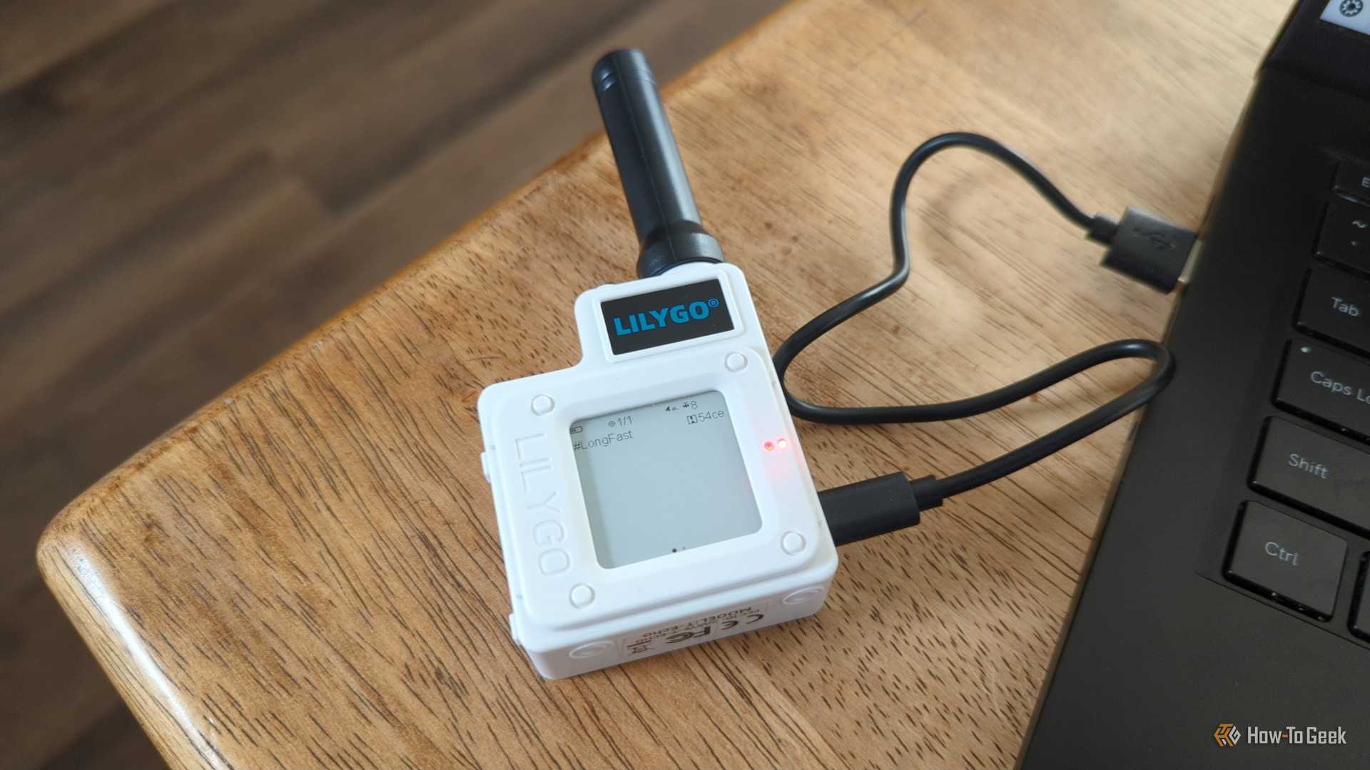 The Lilygo T-Echo LoRa radio on a table plugged into a laptop.