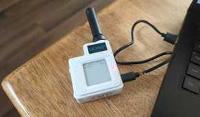 The Lilygo T-Echo LoRa radio on a table plugged into a laptop.