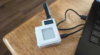 The Lilygo T-Echo LoRa radio on a table plugged into a laptop.