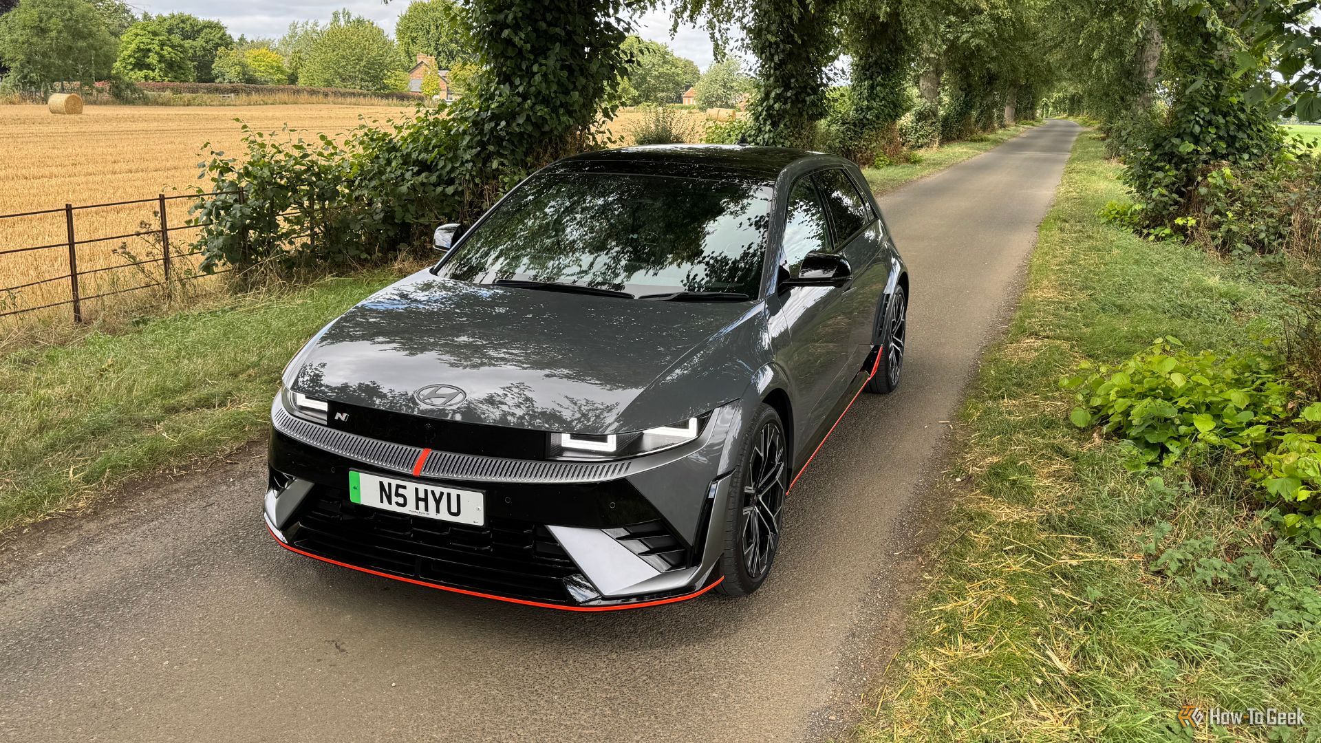 Static front 3/4 shot of a gray 2025 Hyundai Ioniq 5 N parked on a country road lined by trees.