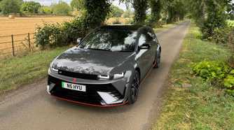 Static front 3/4 shot of a gray 2025 Hyundai Ioniq 5 N parked on a country road lined by trees.