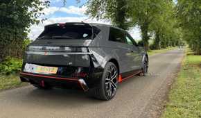 Static rear 3/4 shot of a gray 2025 Hyundai Ioniq 5 N parked on a country road lined with trees.
