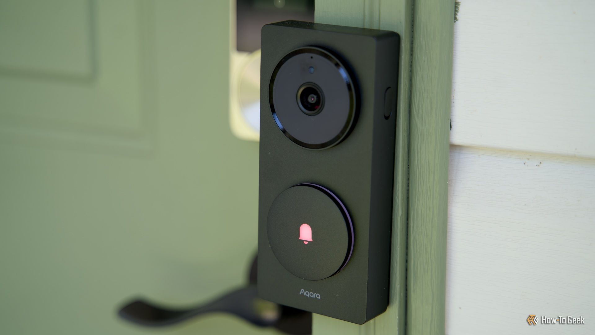 A side view of Aqara's Doorbell Camera Hub G410 mounted to a green door frame.