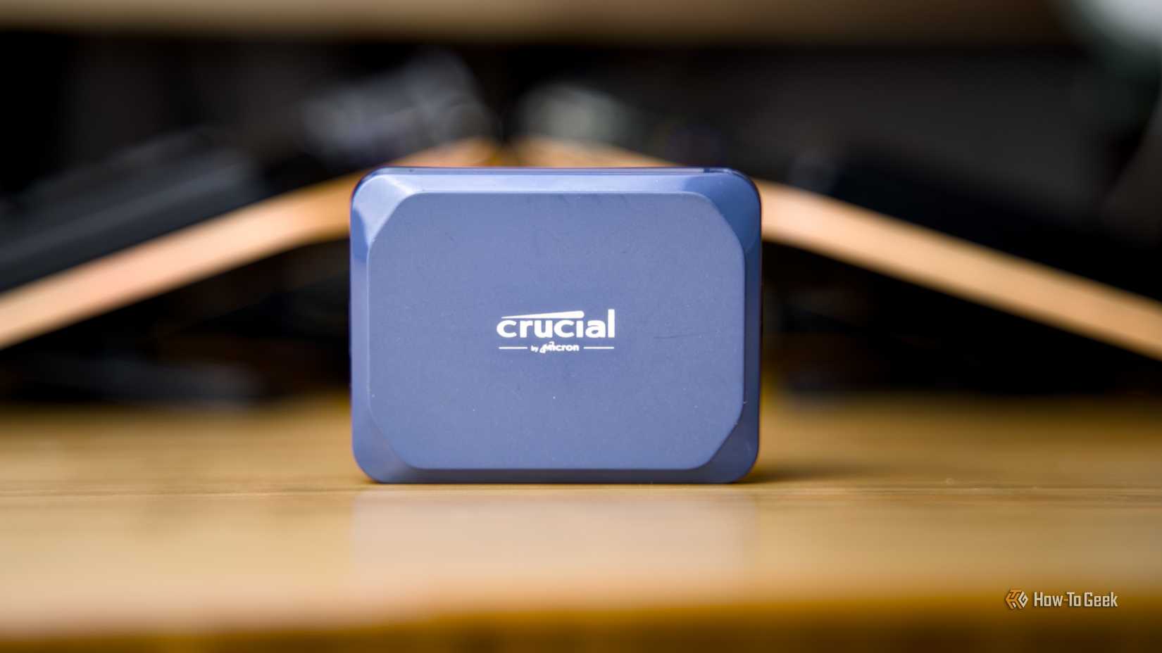 The Crucial X10 portable SSD sitting on a wooden desk.