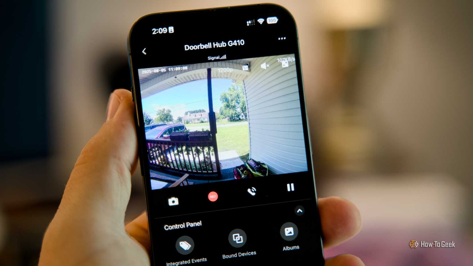 A hand holding an iPhone with the Aqara app open showing the video stream from the Doorbell hub G410.