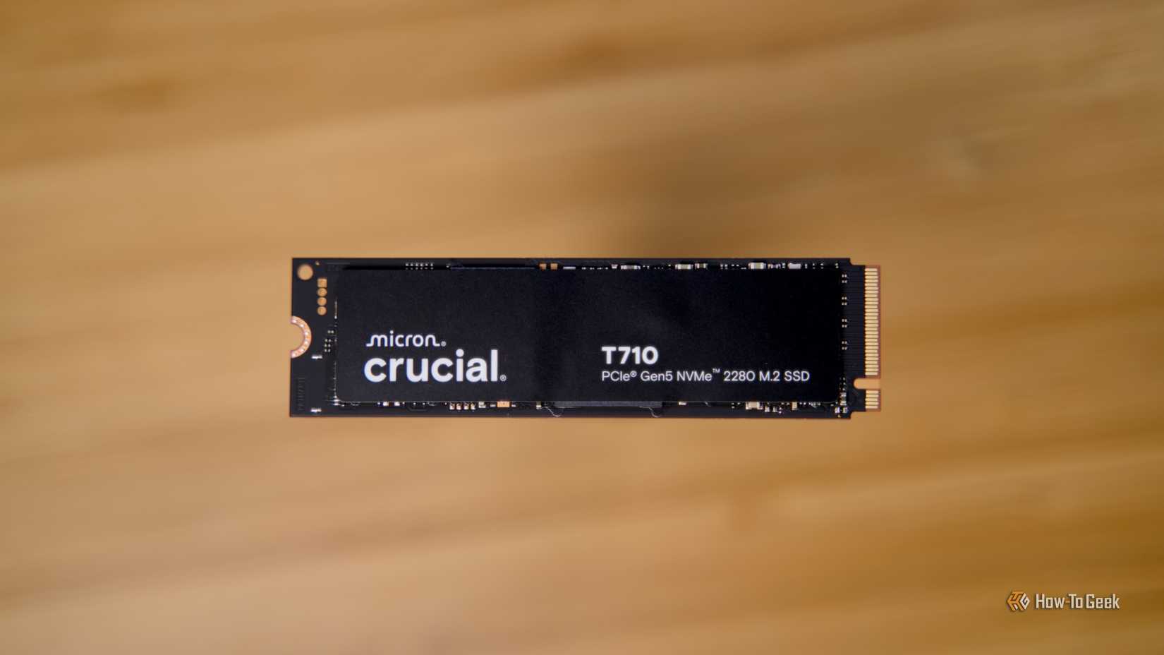 The Crucial T710 PCIe Gen5 NVMe SSD raised off a bamboo desk.