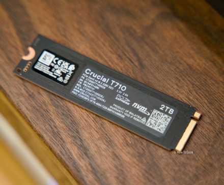 The back of the Crucial T710 NVMe SSD sitting on a walnut shelf.