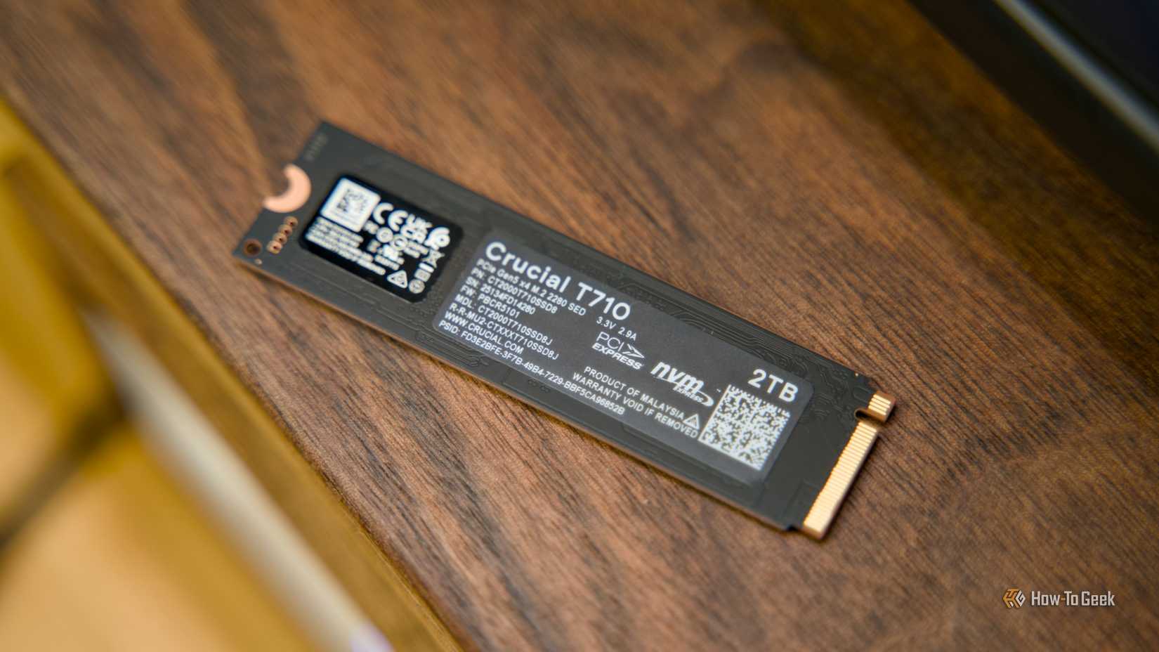 Задняя часть NVMe SSD Crucial T710 на деревянной полке.