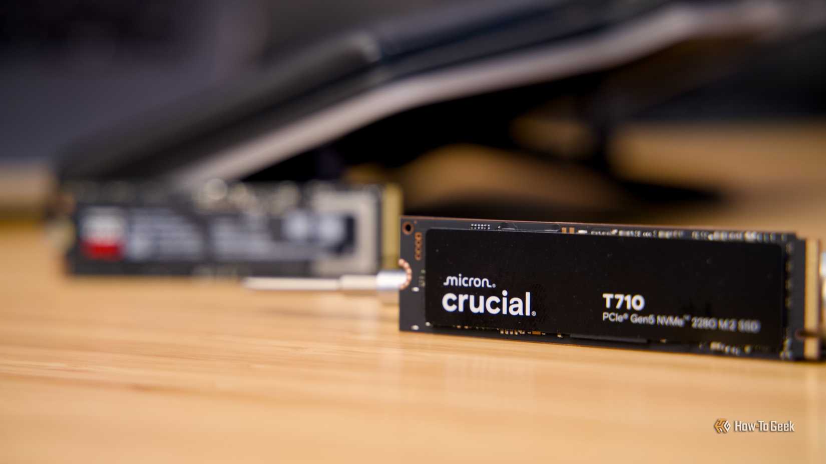 The Crucial T710 NVMe SSD with the Samsung 9100 Pro NVMe SSD blurred in the background.