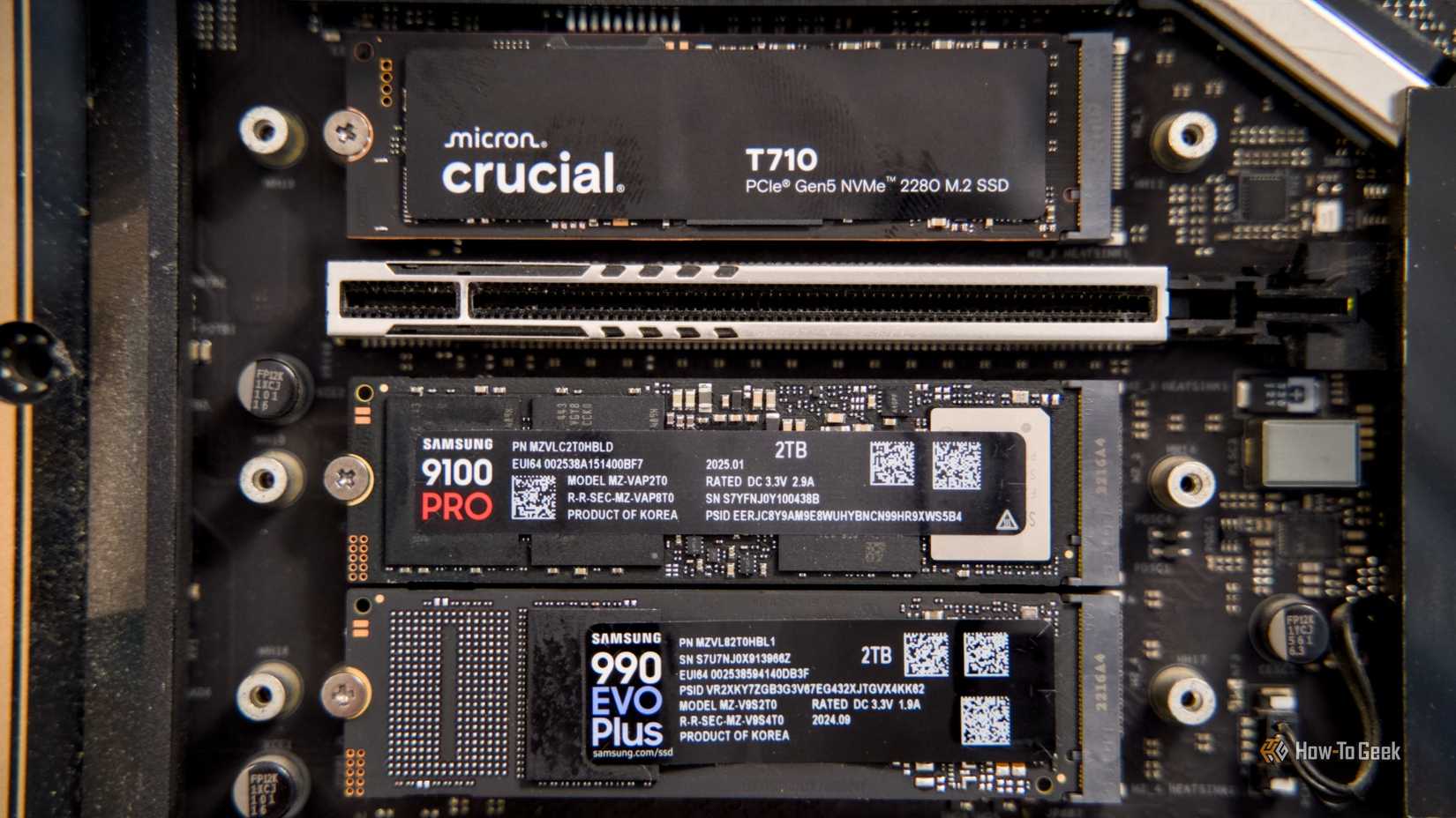 Крупный план Crucial T710, Samsung 9100 Pro и Samsung 990 EVO Plus NVMe SSD, установленных на материнской плате.