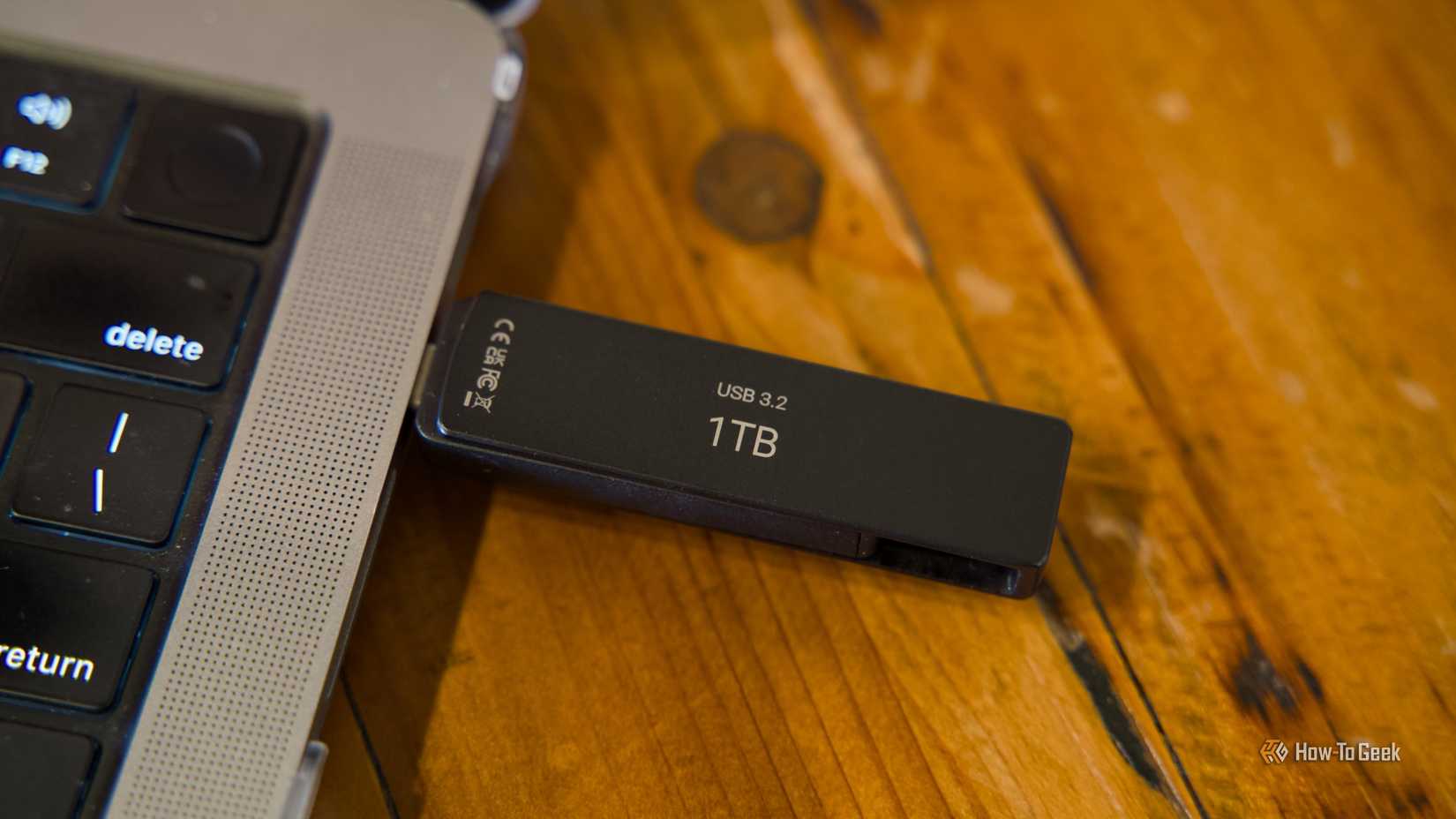 The PNY Duo Link V3 flash drive plugged into a MacBook Pro sitting on a wooden table.