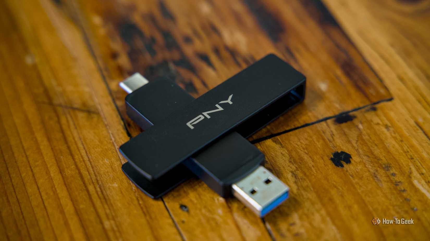 The PNY Duo Link V3 flash drive sitting on a wooden table with both the USB-C and USB-A ports visible.