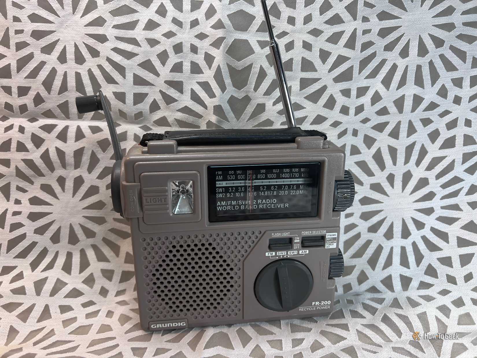 Uma imagem de um rádio cinza movido a bateria com um dínamo de manivela de mão.