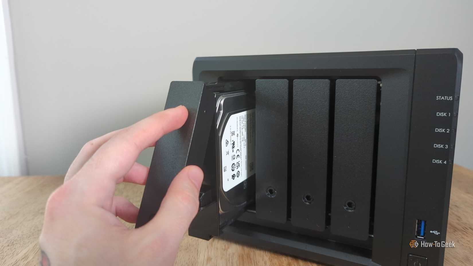 Person's hand placing a drive inside a drive bay on the Synology DS425+ NAS.-2
