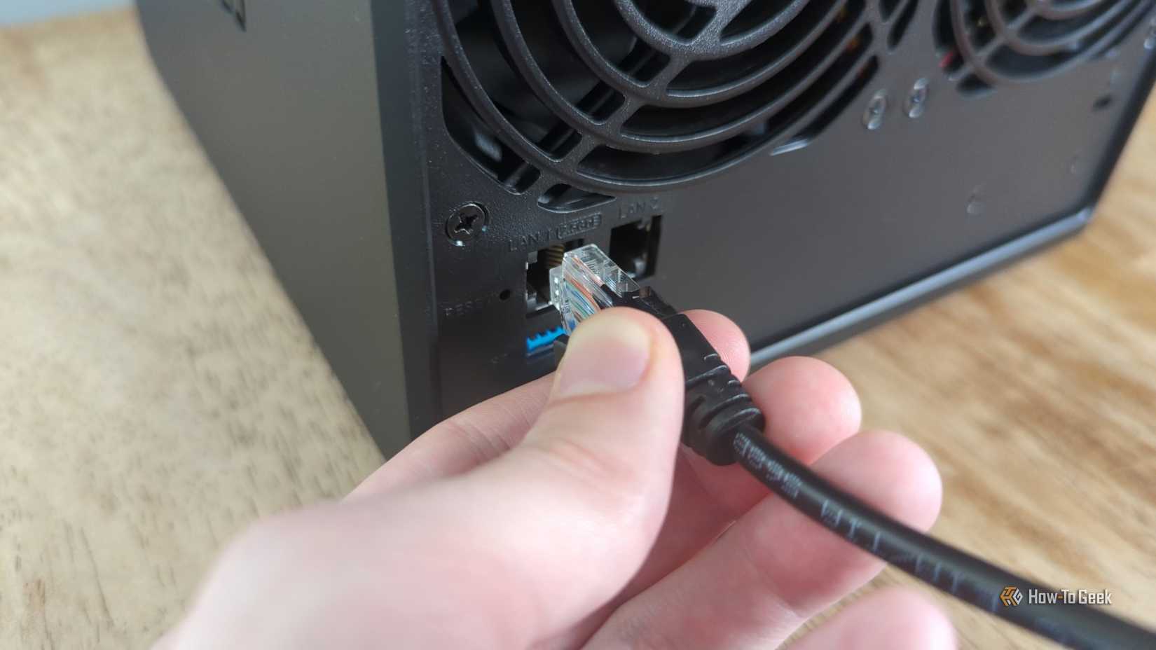 Person's hand plugging an Ethernet cable into a Synology DS425+ NAS.
