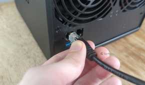 Person's hand plugging an Ethernet cable into a Synology DS425+ NAS.