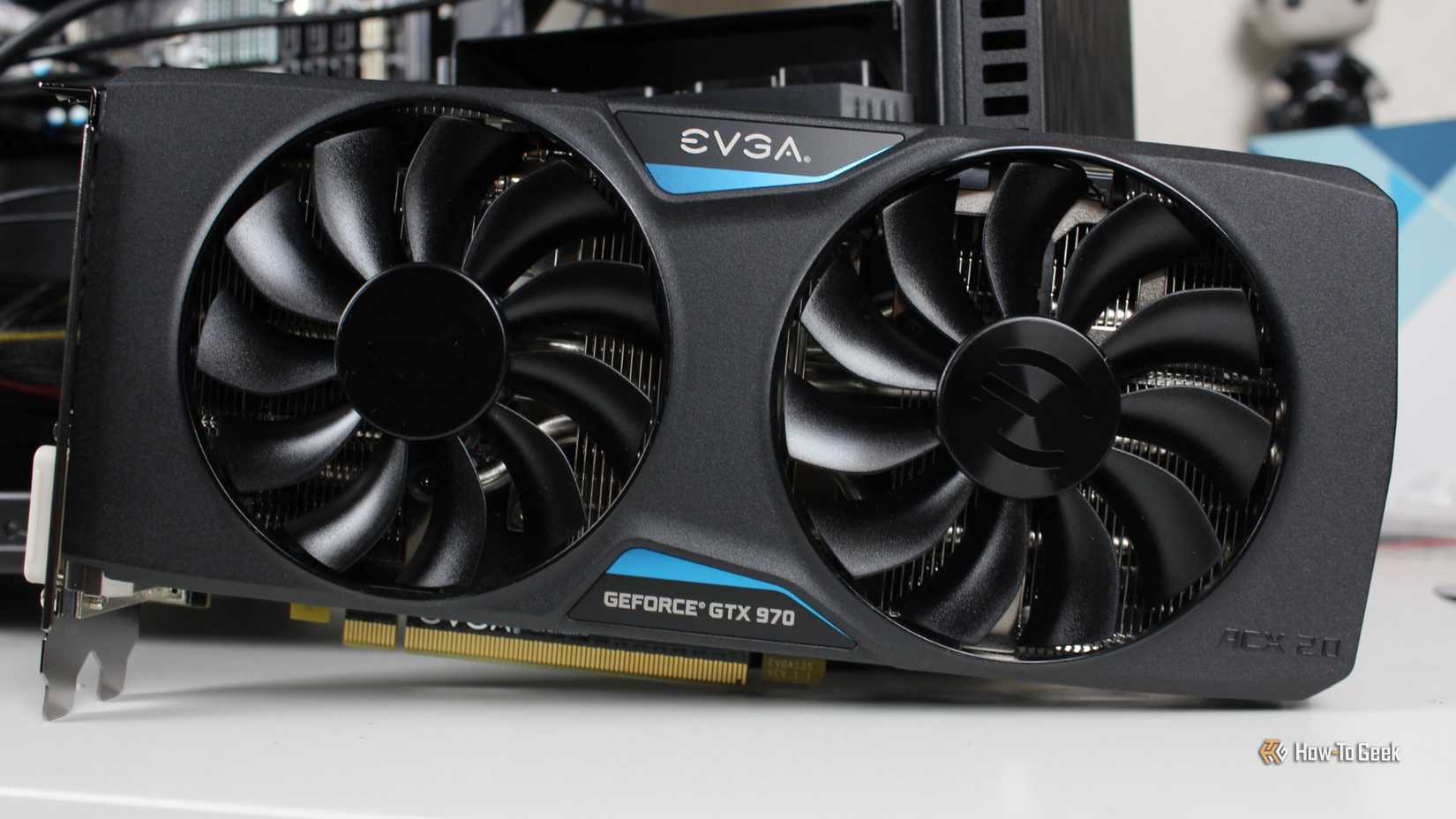 The EVGA NVIDIA GeForce GTX 970 SSC GAMING ACX 2.0 graphics card sitting on a desk.