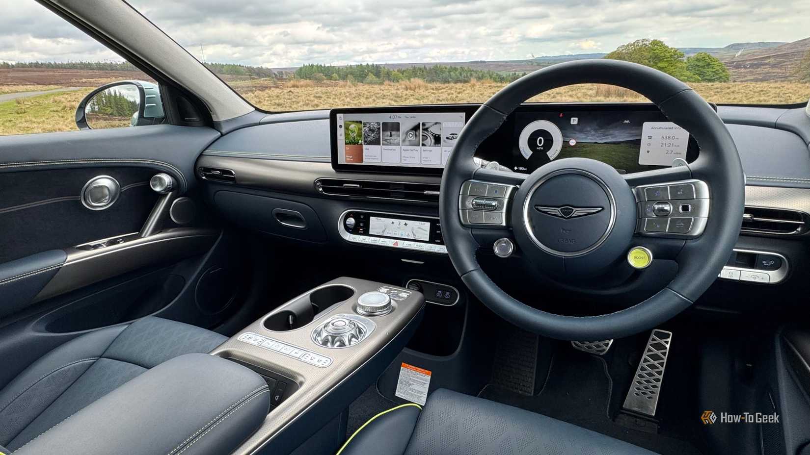 Disparo dentro de la cabina de un Genesis Gv60 2025 desde el asiento del conductor que muestra los asientos delanteros y el tablero.