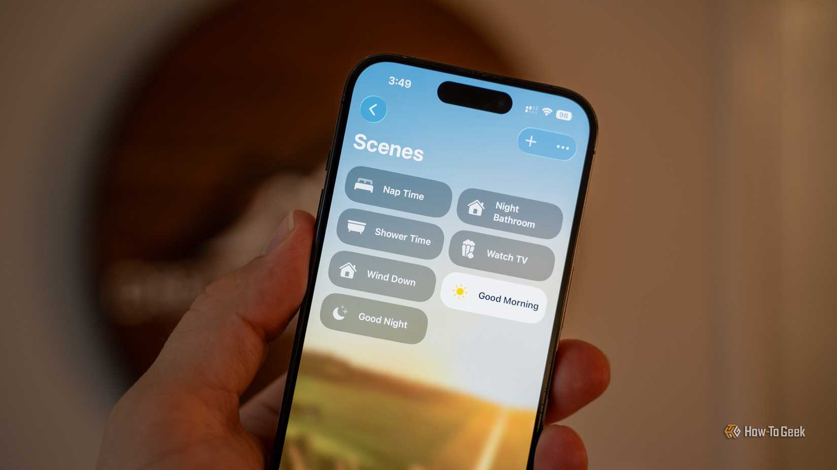 An iPhone held in a hand showing the scenes in the Apple Home app.