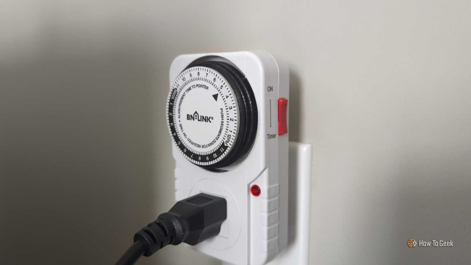 BN-Link mechanical timer on an outlet with an electrical cord plugged into it.