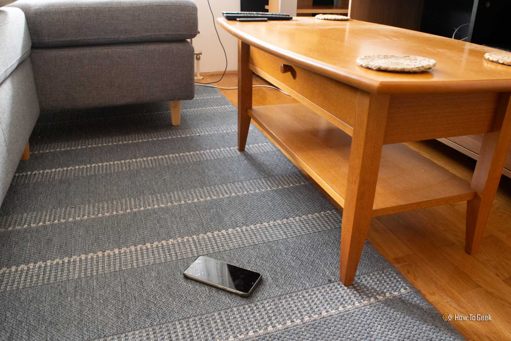 A Samsung Galaxy S21 FE lying on a carpet next to a coffee table. 