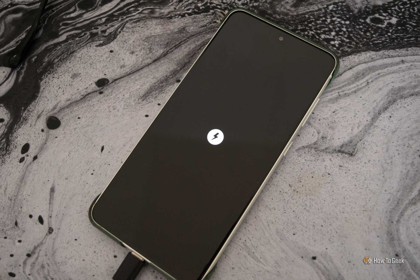 A Galaxy S21 FE that's turned off charging with the charging icon showing on its screen. 