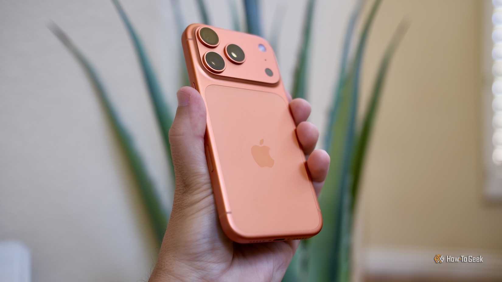 A hand holding the Apple iPhone 17 Pro in orange