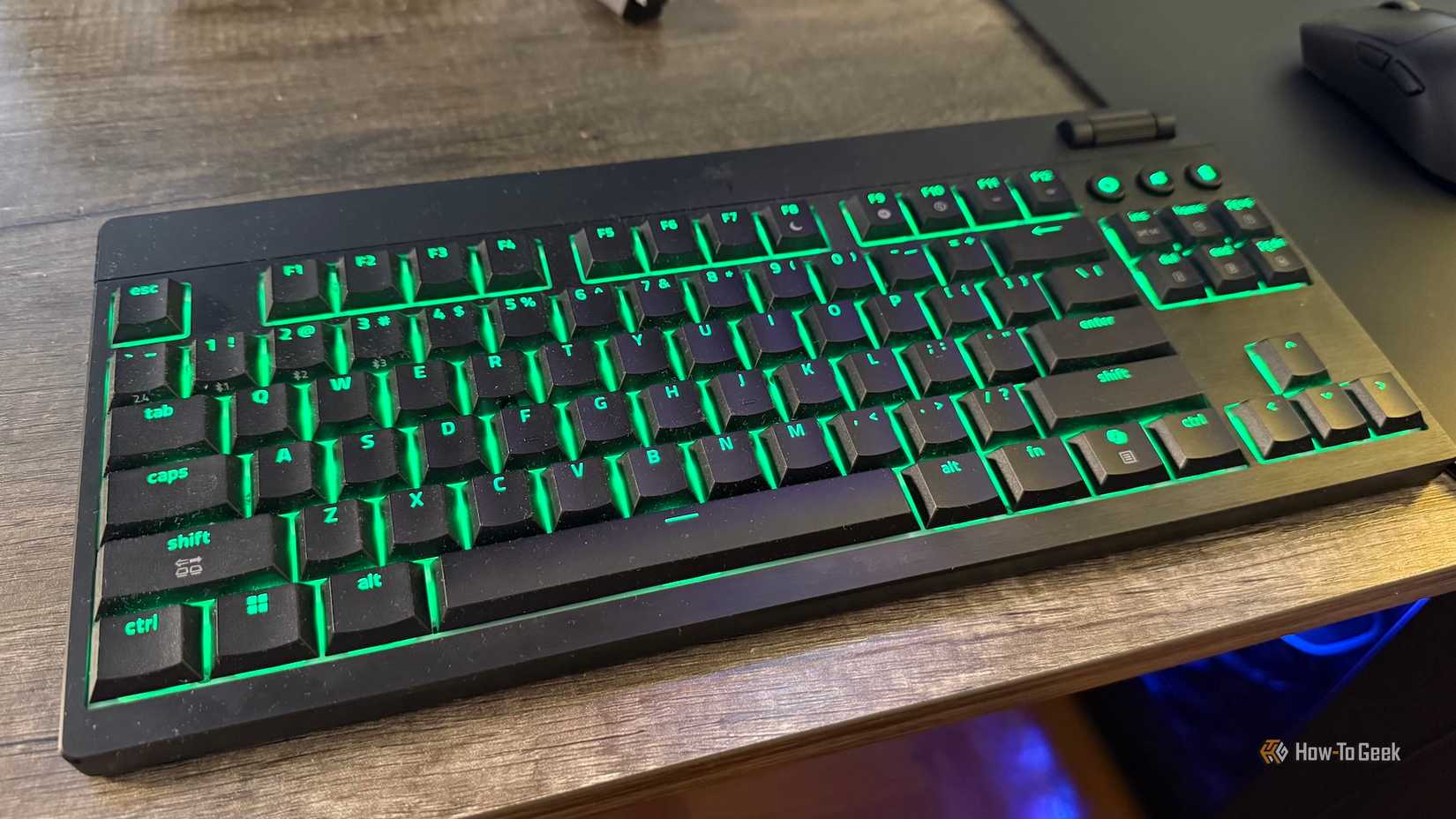 O Razer Blackwidow V4 Hyperspeed sem tenkey de baixo perfil em uma mesa com iluminação verde RGB.