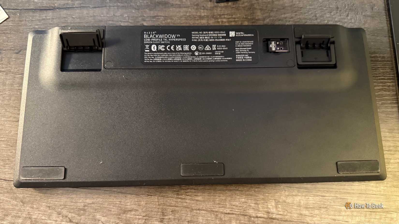 A parte inferior do Razer Blackwidow V4 de baixo perfil de tenkeylespeed sem tenkey com os pés ajustáveis ​​e o slot de 2,4 GHz.