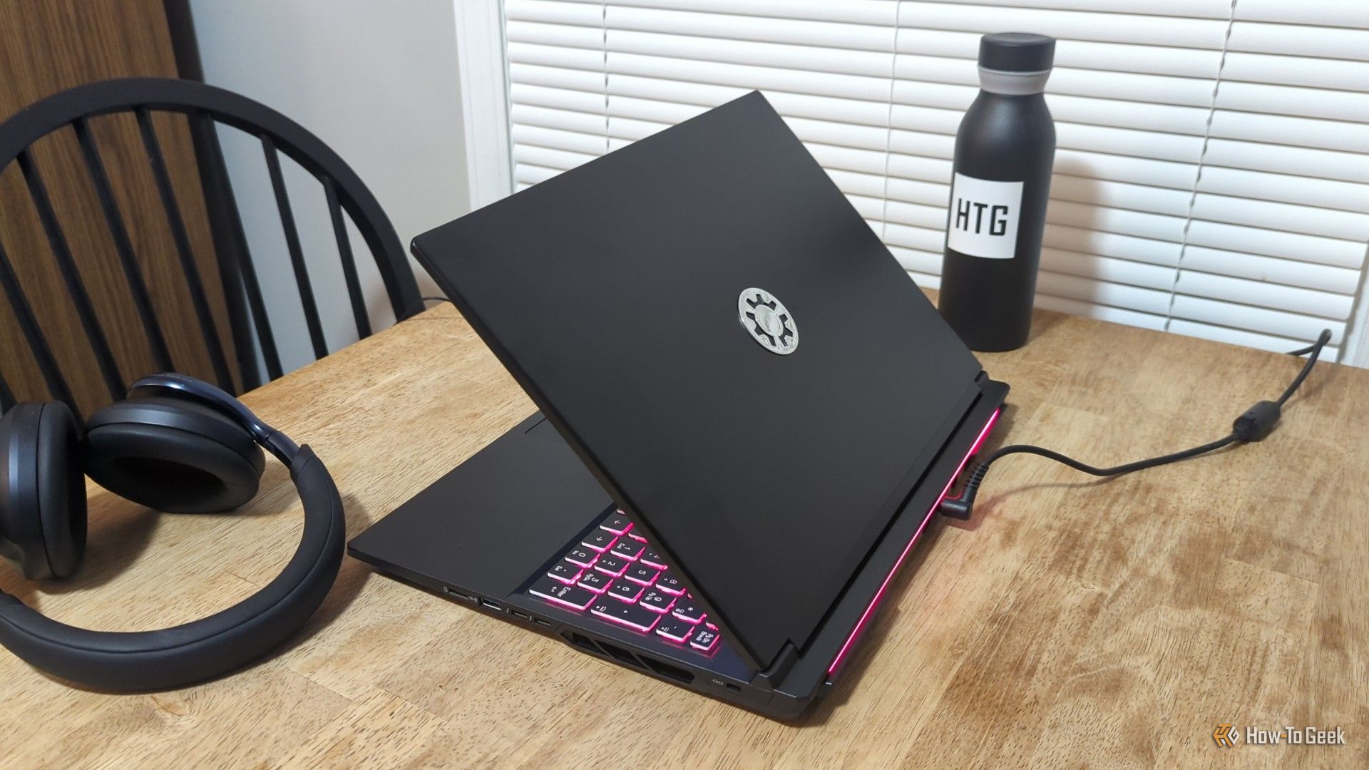 The Kubuntu Focus M2 Gen 6 laptop on a table next to a pair of headphones.