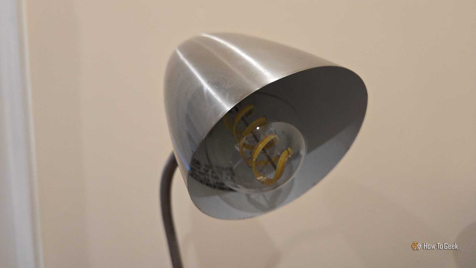Cync Clear Full Color Direct Connect A19 smart bulb in a metal desk lamp.