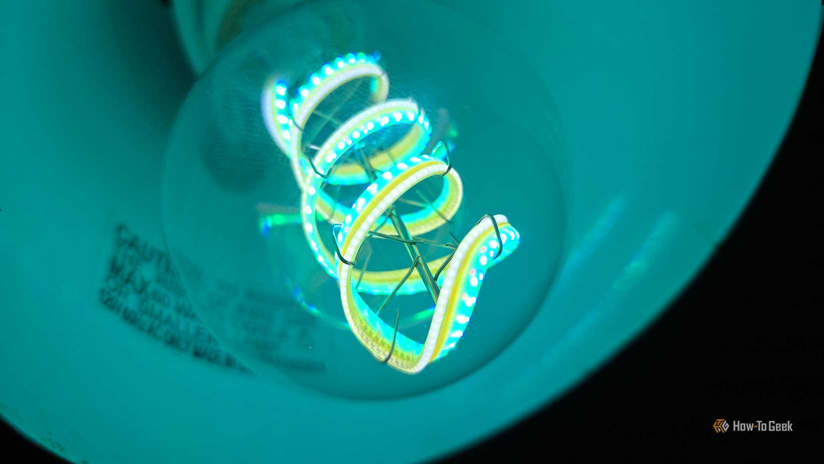 Cync Clear Full Color Direct Connect smart bulb in a lamp, glowing blue.