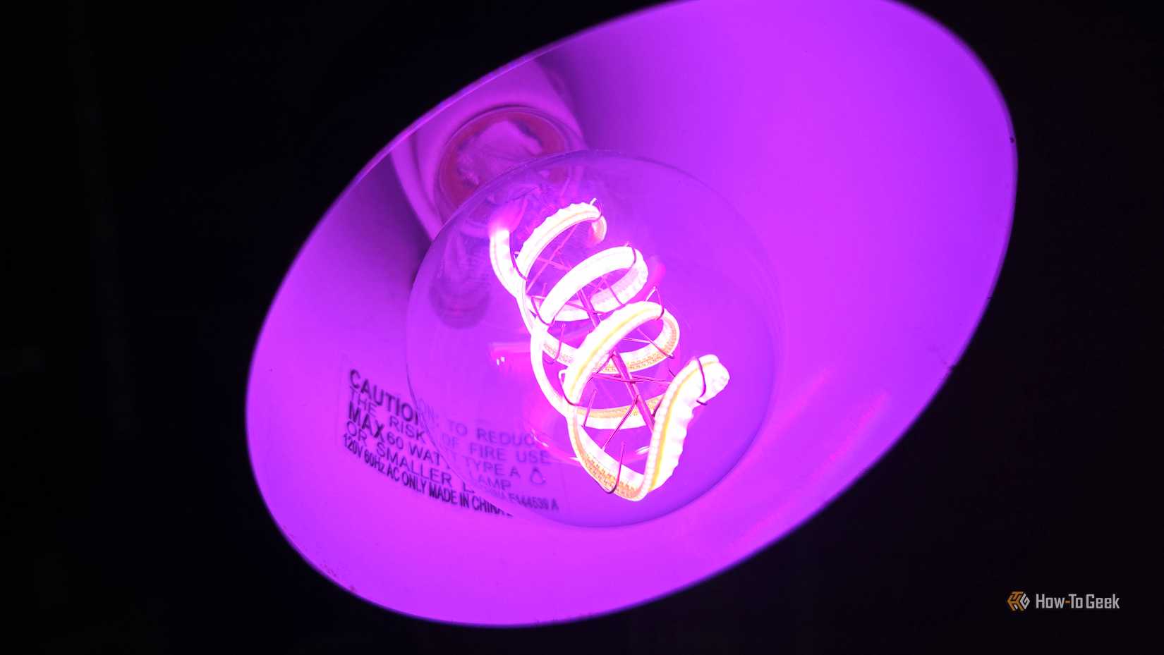 Cync Clear Full Color Direct Connect smart bulb in a lamp, glowing purple.