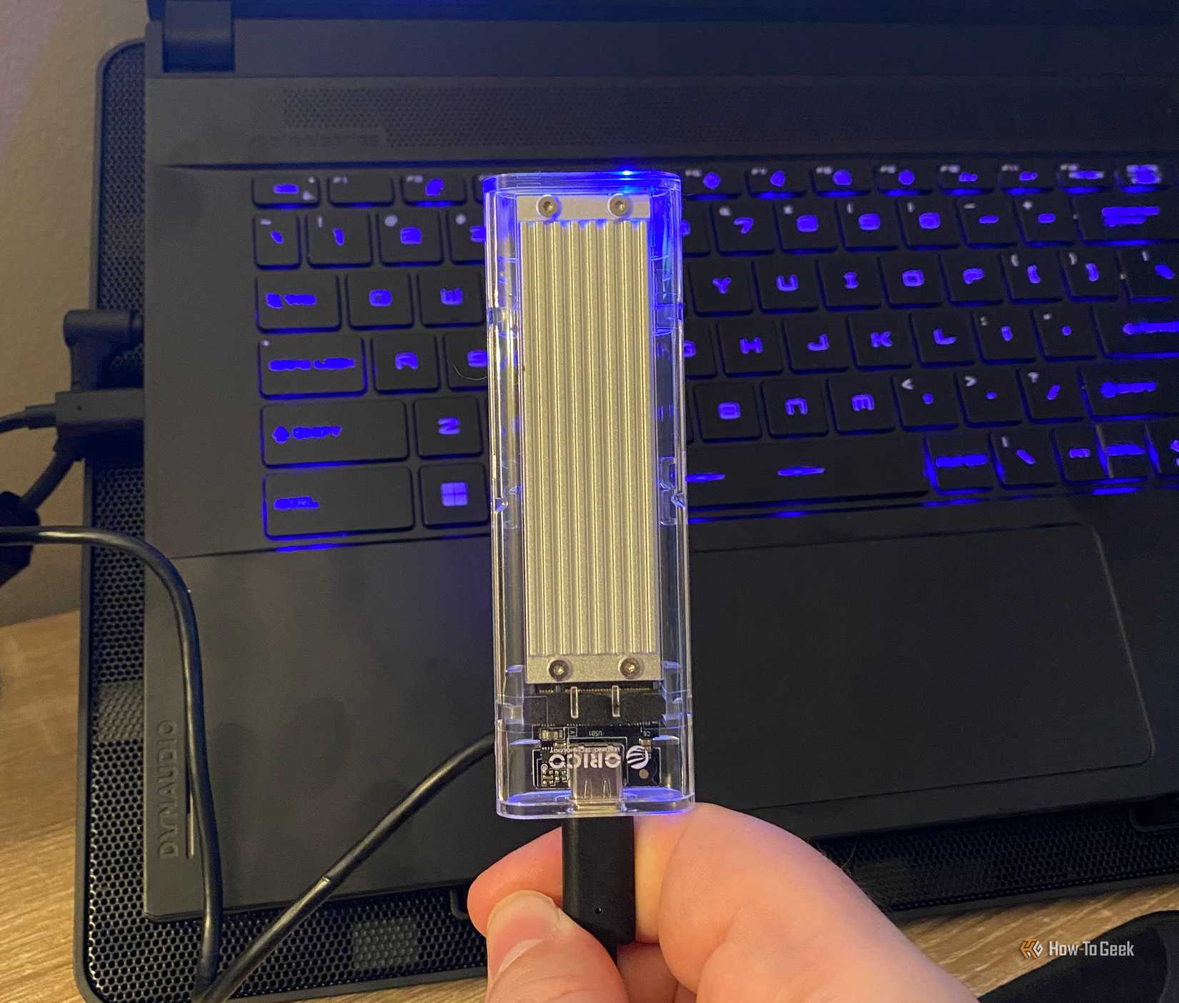 A USB NVMe SSD in front of a gaming laptop
