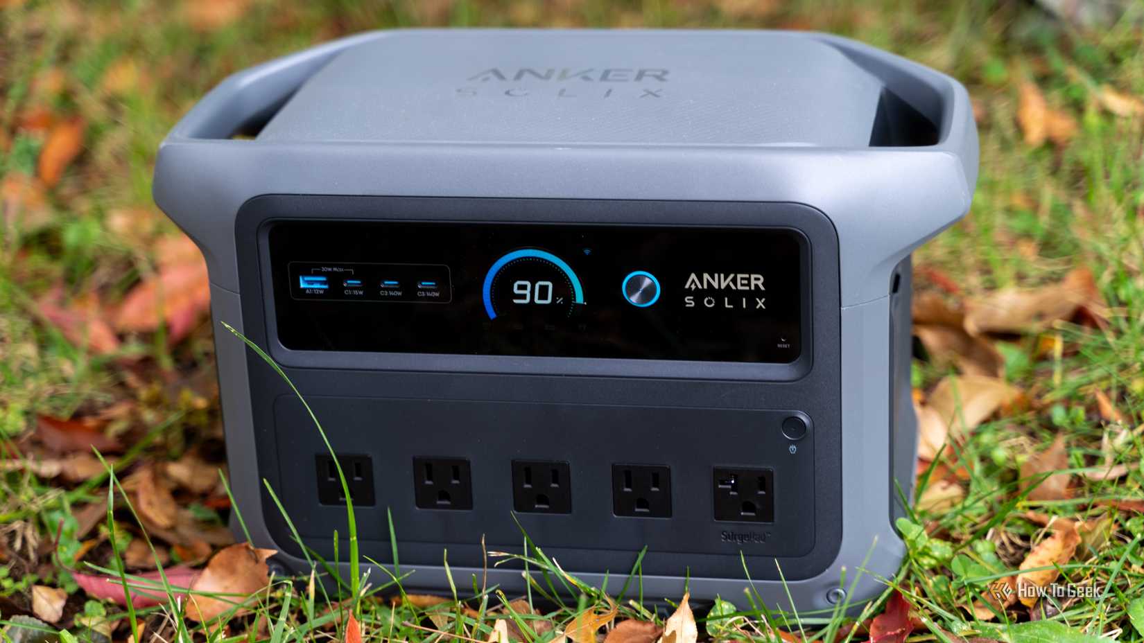 A7301119The front of the Anker SOLIX C1000 Gen 2 portable power station with the display turned on sitting in grass with leaves.