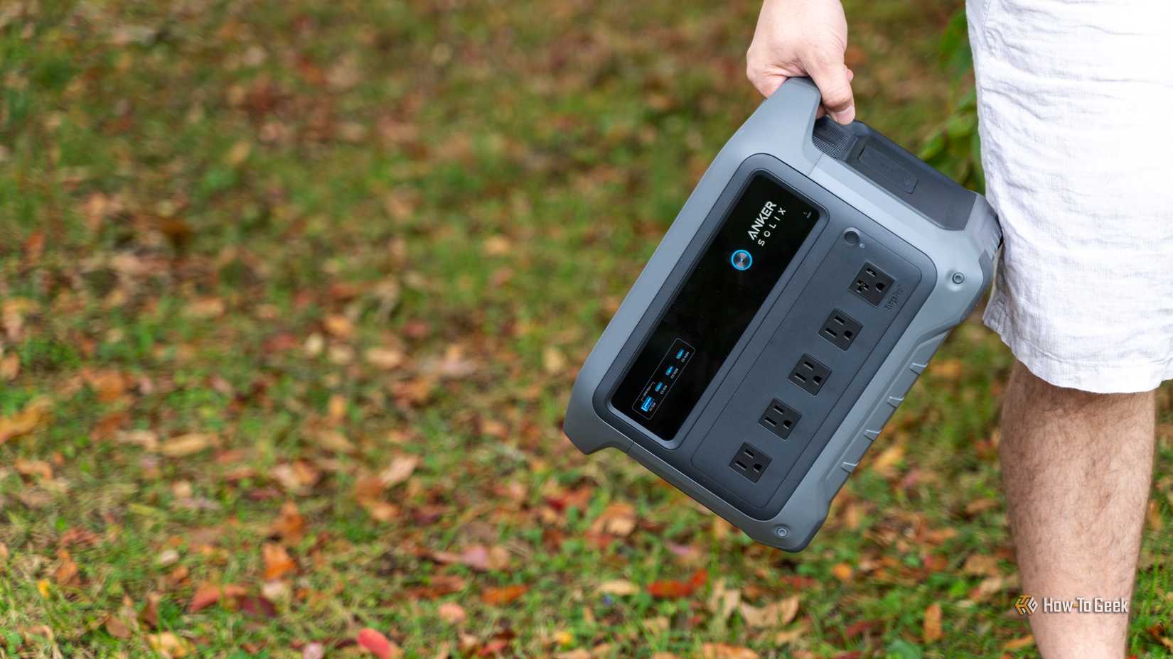 A person holding the Anker SOLIX C1000 Gen 2 power station in the grass.