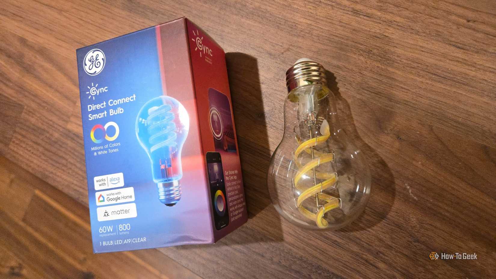 Cync Clear Full Color Direct Connect smart bulb next to its retail box.