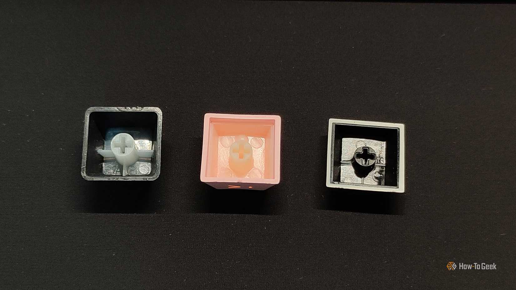Bottom view of three double-shot PBT keycaps with drastically different amounts of injection.